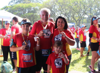 Corrida de rua Global Energy Race, deve gerar doação de 1 milhão de fatias de pão Família carregando medalha no peito após o término da corrida